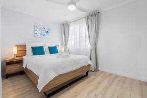 a white bedroom with a bed and a window at Azure beachside Escape in Marcoola