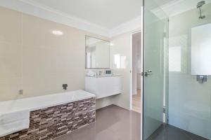 a bathroom with a tub and a sink and a mirror at Azure beachside Escape in Marcoola