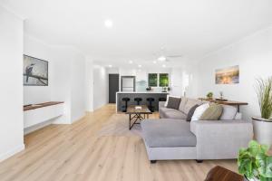 a white living room with a couch and a kitchen at Azure beachside Escape in Marcoola +12 photos