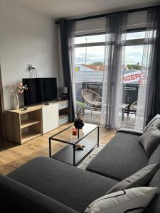 a living room with a couch and a tv at Lily Beach Apartman in Balatonlelle