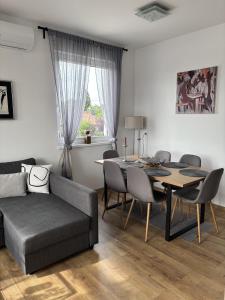 a living room with a couch and a table and chairs at Lily Beach Apartman in Balatonlelle