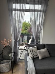 a living room with a couch and a large window at Lily Beach Apartman in Balatonlelle