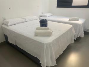 two beds with white sheets and towels on them at Mini Palacete in Ribeirão Preto +59 photos