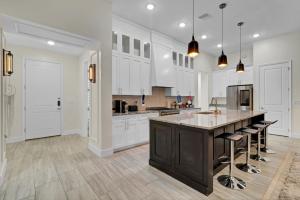 a kitchen with white cabinets and a large island with bar stools at SpaceX R4 Shared in Orlando