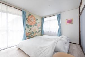 a bedroom with a white bed and a window at Joy House in Matsumoto