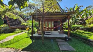 a small house with a tree in front of it at Green Haven Homestay in Tetebatu
