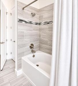 a white bath tub in a bathroom with a shower curtain at SpaceX R3 Shared in Orlando