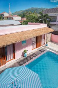 a swimming pool with an umbrella and a building at Hyde Boutique Hotel in Kuta Lombok