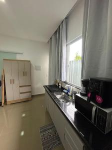 a kitchen with a sink and a microwave and a window at Studio CG Tingui 1 in Estação Inhoaíba