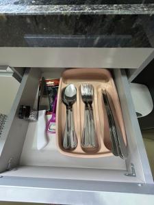 a tray with utensils in a drawer under a table at Studio CG Tingui 1 in Estação Inhoaíba +1 photo