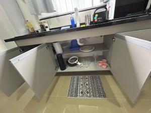 a kitchen with white cabinets and a drain in the floor at Studio CG Tingui 1 in Estação Inhoaíba