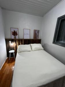 a bedroom with a large white bed in a room at Hostel e Pousada das Rosas Nova Hartz RS in Nova Hartz