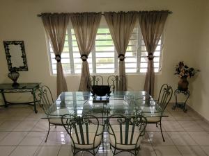 a dining room with a glass table and chairs at Villa in Miradero in Mayaguez