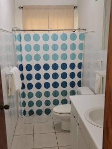 a bathroom with a toilet and a blue and white shower curtain at Villa in Miradero in Mayaguez +45 photos