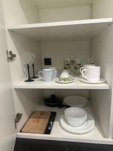 a white shelf with plates and cups and dishes at Historical Apartments by Stepan Fedak in Lviv