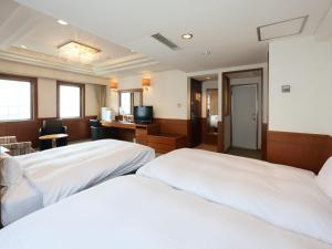 a hotel room with two beds and a desk at Tabist THE GREEN SAPPORO in Sapporo