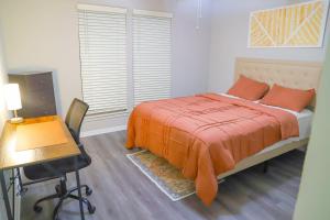 a bedroom with a bed with an orange blanket and a desk at Cozy ATL Retreat in Decatur