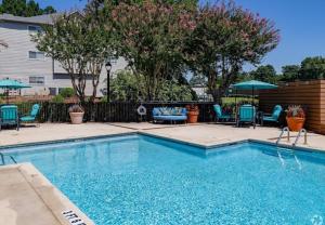 a swimming pool with chairs and umbrellas in a yard at Cozy ATL Retreat in Decatur