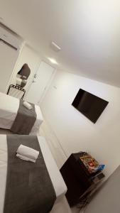 a small white room with two beds and a chair at Hotel Vistta Iracema in Fortaleza