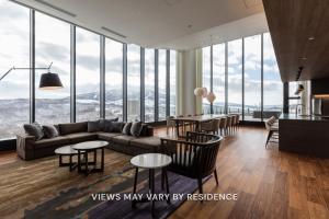 a living room with a couch and tables and windows at The Vale Rusutsu in Rusutsu