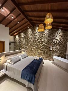 a bedroom with a bed and a stone wall at Pousada Yvanna in Pirenópolis +41 photos