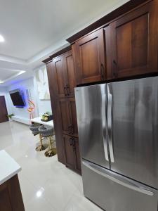 a kitchen with a stainless steel refrigerator and wooden cabinets at House of Harmony in Portmore