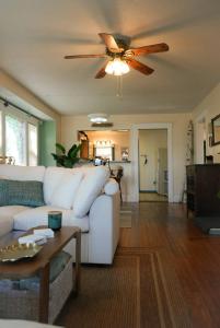 a living room with a white couch and a ceiling fan at Bluffton Breeze Cottage in Muskegon