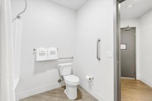 a white bathroom with a toilet and a glass door at Kasa Capitol Hill Seattle in Seattle
