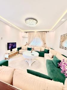 a living room with green couches and a tv at Luxury Villa with Pool & Garden5km from Cabo in Tétouan
