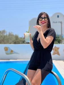 a woman in a black dress holding a drink at Stella's place, Vlichada in Vlychada