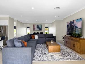 a living room with a blue couch and a tv at Wrenwood in Abernethy