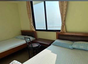 a room with two beds and a window at Hotel Shangbola in Pāti Bhanjyāng