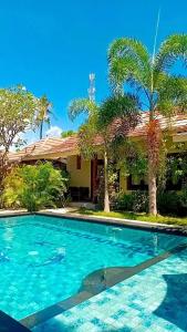 a swimming pool in front of a house with palm trees at Villa Kinagu in Gili Meno