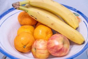 a bowl of fruit with bananas apples and oranges at Hotel Casagrande in Paysandú