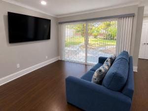 a living room with a blue couch and a flat screen tv at Mid City ranch! Huge backyard/Private pool! in Baton Rouge