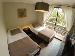 a bedroom with two beds and a large window at Apart Hotel Gran Pacifico in La Serena +88 photos