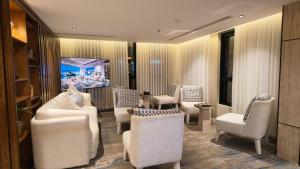 a living room with white chairs and a fish tank at فندق لامار بارك - العليا in Tabuk
