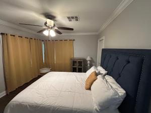 a bedroom with a bed with a ceiling fan at Mid City ranch! Huge backyard/Private pool! in Baton Rouge +25 photos
