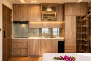a kitchen with wooden cabinets and pink flowers on a table at W Premium Nha Trang in Nha Trang
