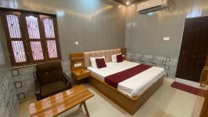 a bedroom with a bed and a desk and a chair at Tripathi's Rampath Inn Ayodhya in Ayodhya
