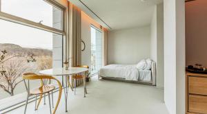 a bedroom with a table and a bed and a window at Ripple Boutique Hotel in Yangpyeong