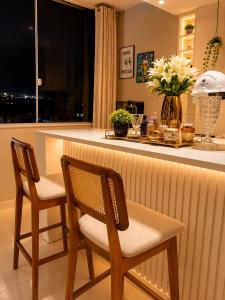 a kitchen with two chairs and a counter with flowers at diRoma Luxo Oficial Apt mais diRoma Acqua Park e Splash e Slide , 3 parques Aquáticos , Roupa de Cama e Toalhas, Parcelamos até 12x no Cartão de Crédito sem Juros , Aceitamos Pet in Caldas Novas +9 photos