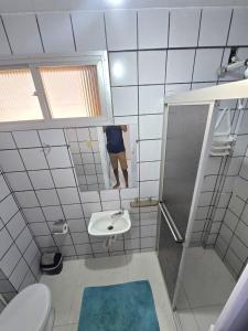 a bathroom with a sink and a toilet and a mirror at Praia Morro Katia apartamentos - Edificio Porto Belo in Guarapari