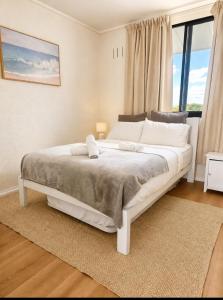 ein weißes Bett in einem Zimmer mit großem Fenster in der Unterkunft Semaphore beachfront in Semaphore