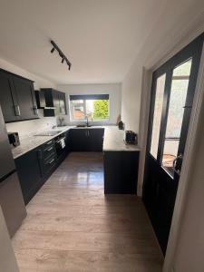 a large kitchen with black cabinets and a large window at Cosy 4 bedroom house in Marshside +10 photos