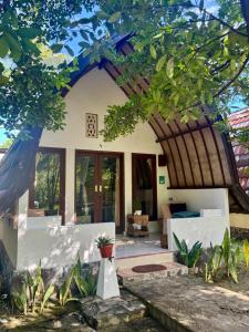 a house with a porch and a living room at Rising Sun Bungalows in Gili Meno