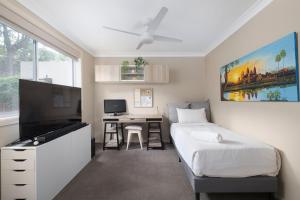 a bedroom with a bed and a desk and a television at Chelsea Poolside and Tennis in Nelson Bay