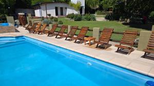 a row of chairs sitting next to a swimming pool at Rio Cabañas in Huerta Grande