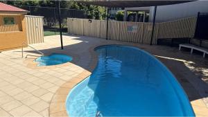 a swimming pool in a yard with a fence at Chelsea Poolside and Tennis in Nelson Bay