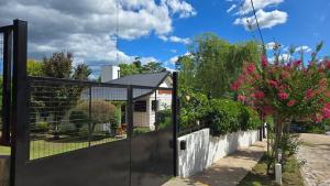 a fence in front of a house with pink flowers at Rio Cabañas in Huerta Grande